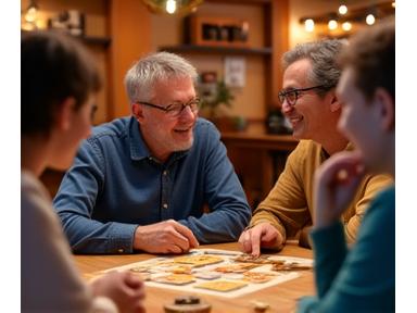 Group of adults laughing and playing a board game at a cozy cafe